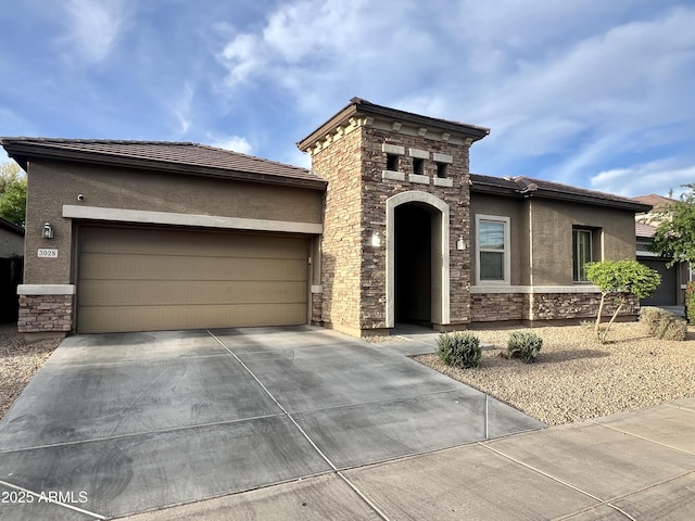 view of front of property featuring a tile roof, stucco siding, stone siding, driveway, and a garage