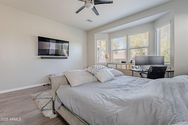 bedroom featuring baseboards, visible vents, wood finished floors, and multiple windows