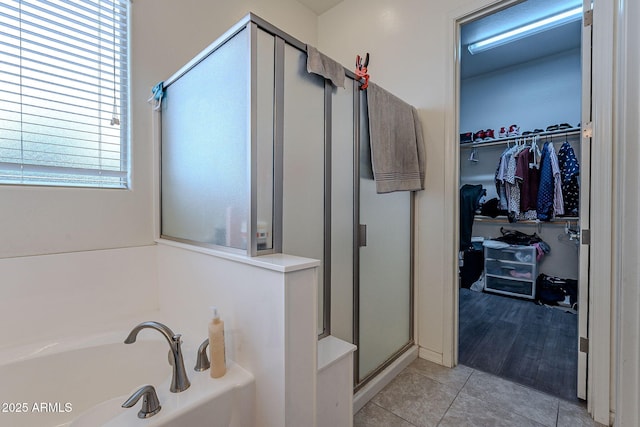 bathroom featuring a bath, tile patterned floors, a spacious closet, and a shower stall