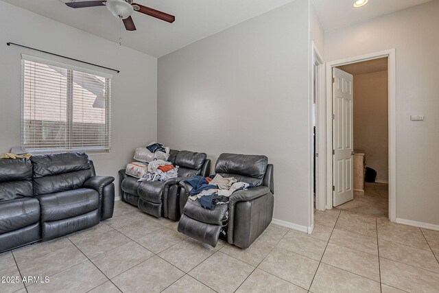living area with a ceiling fan, light tile patterned floors, and baseboards
