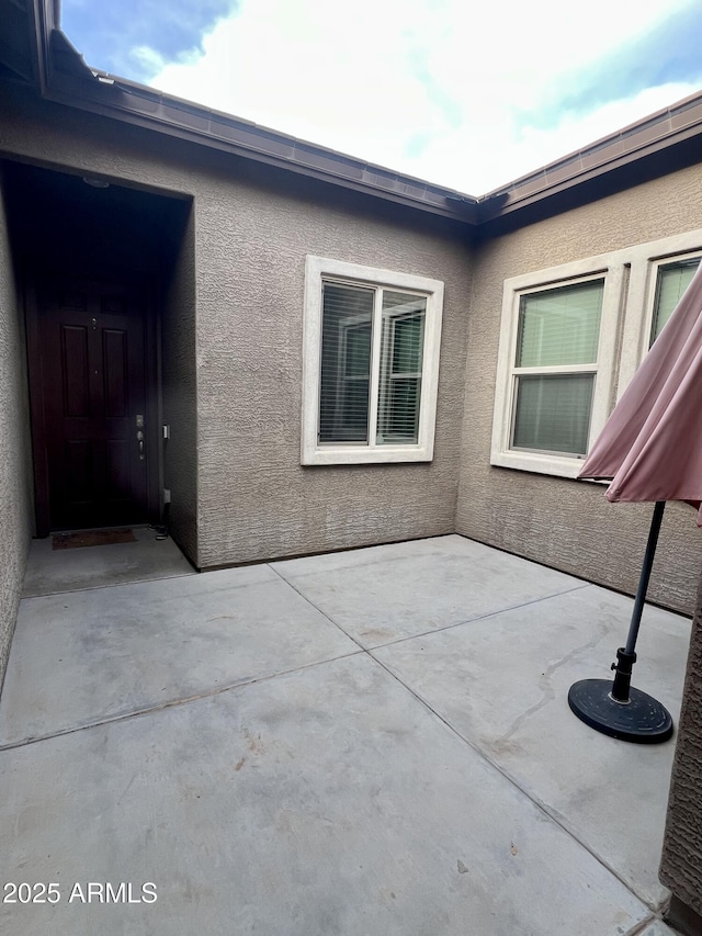 exterior space with stucco siding and a patio