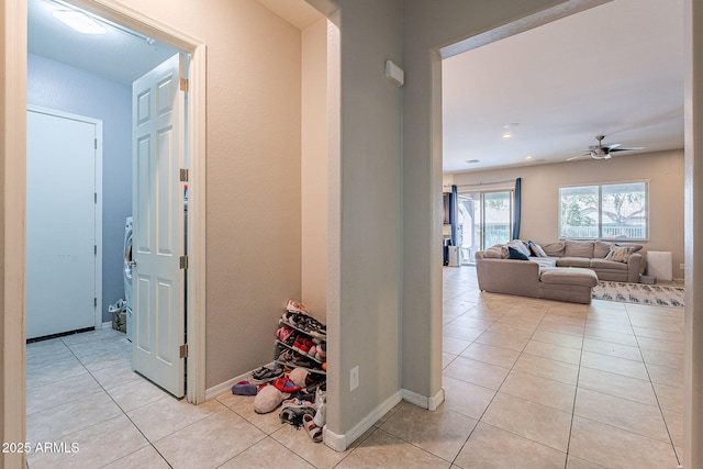 hall featuring light tile patterned floors and baseboards