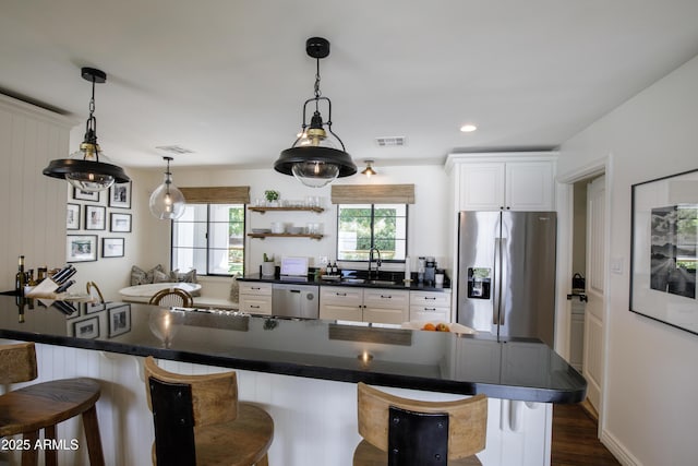 kitchen featuring a breakfast bar, dark countertops, stainless steel appliances, and visible vents