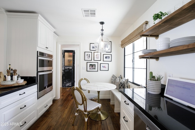 interior space featuring dark countertops, open shelves, stainless steel double oven, and visible vents