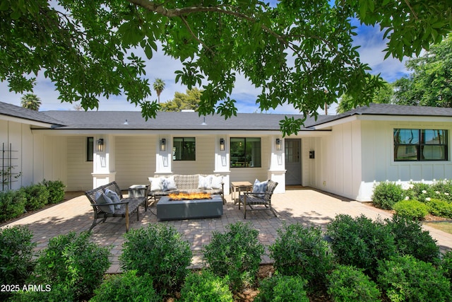 back of property with board and batten siding, an outdoor living space with a fire pit, and a patio