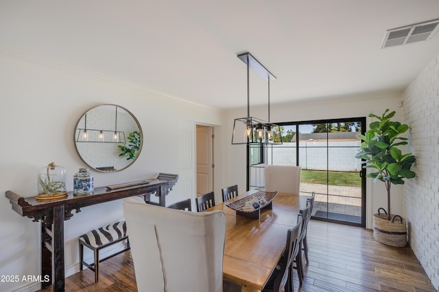 dining space with wood finished floors, visible vents, a notable chandelier, and crown molding