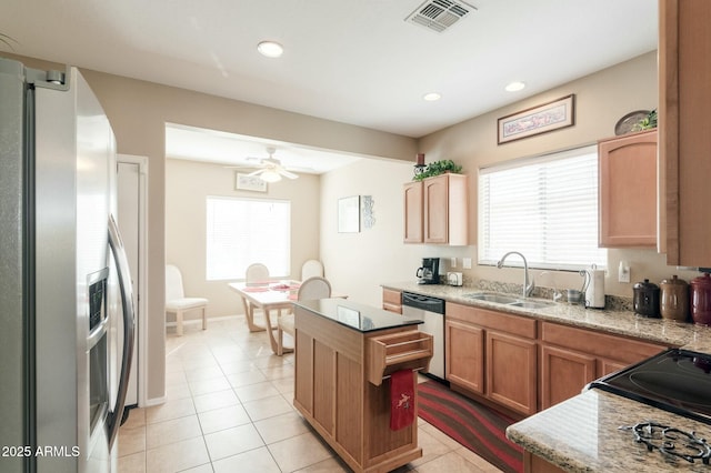 kitchen with light tile patterned flooring, sink, a kitchen island, ceiling fan, and stainless steel appliances