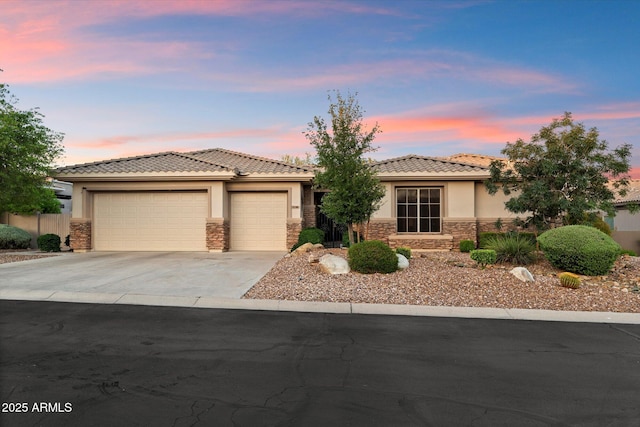 11193 N 121st Way, Scottsdale, AZ 85259 - view of front of home featuring stone siding, an attached garage, a tiled roof, driveway, and stucco siding