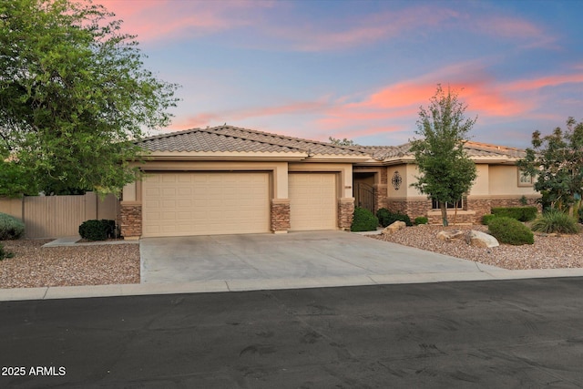 11193 N 121st Way, Scottsdale, AZ 85259 - view of front of house featuring stone siding, an attached garage, concrete driveway, stucco siding, and a tile roof