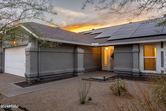 view of front of property with a garage and solar panels