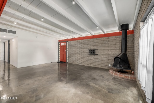 5739 N 11th St, Phoenix, AZ 85014 - unfurnished living room featuring brick wall, concrete floors, a wood stove, and beam ceiling