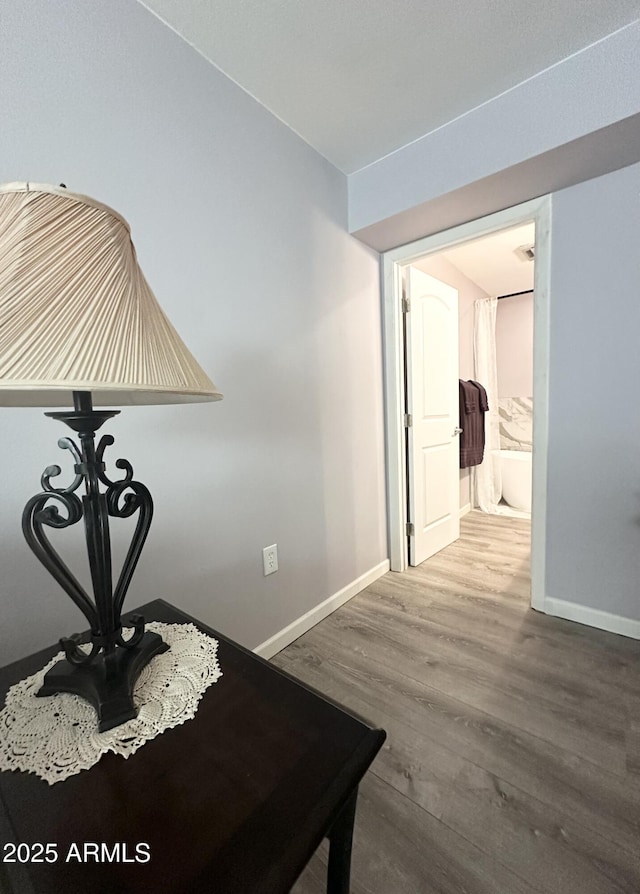 corridor with baseboards and wood finished floors