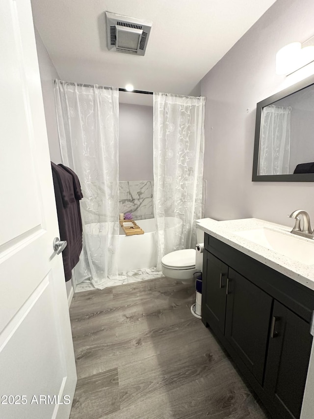 bathroom featuring visible vents, toilet, shower / bath combo with shower curtain, vanity, and wood finished floors