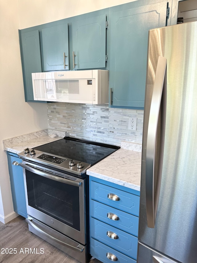 kitchen with stainless steel appliances, range hood, blue cabinets, and tasteful backsplash