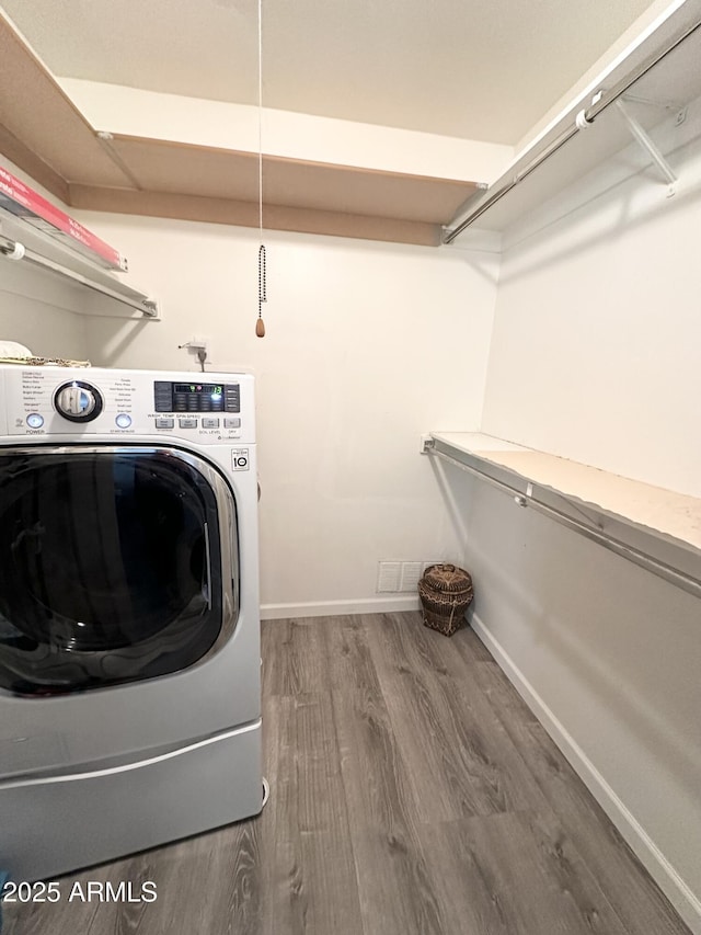 laundry area with washer / dryer, laundry area, baseboards, and wood finished floors