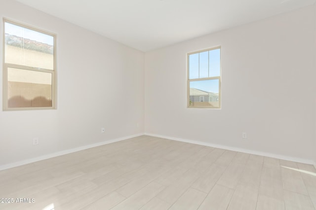 spare room featuring light hardwood / wood-style floors and a healthy amount of sunlight