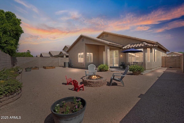 4459 E Desert Wind Dr, Phoenix, AZ 85044 - back of house at dusk featuring an outdoor fire pit, a patio area, stucco siding, and a fenced backyard