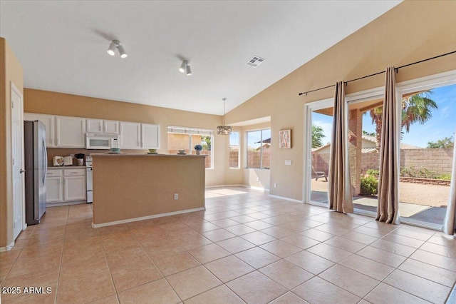 4459 E Desert Wind Dr, Phoenix, AZ 85044 - kitchen with white microwave, freestanding refrigerator, light tile patterned flooring, white cabinets, and hanging light fixtures