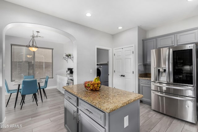 kitchen with arched walkways, a center island, washer / clothes dryer, smart refrigerator, and decorative light fixtures