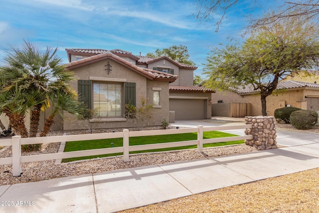 mediterranean / spanish home featuring a fenced front yard, a tile roof, stucco siding, concrete driveway, and an attached garage