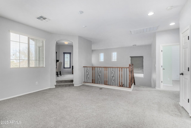 unfurnished room featuring arched walkways, light carpet, visible vents, and recessed lighting