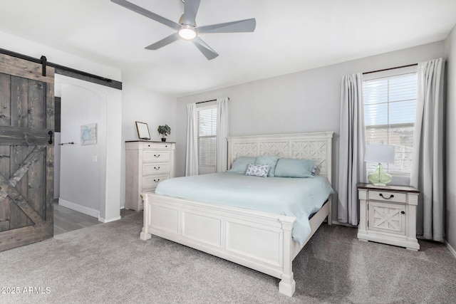 bedroom featuring a ceiling fan, carpet flooring, baseboards, and a barn door