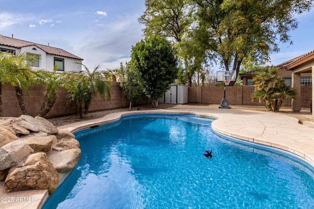 view of pool featuring a storage shed, a patio, a fenced backyard, and a fenced in pool