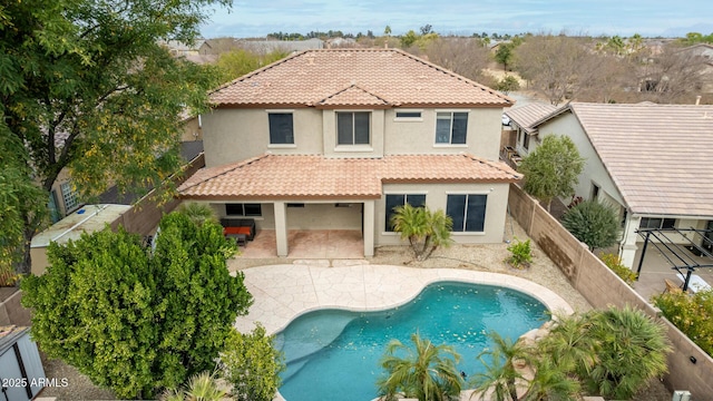 back of house with a fenced in pool, stucco siding, a patio area, a fenced backyard, and a tiled roof