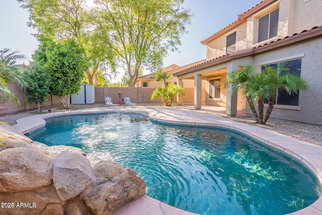 view of swimming pool with a storage shed, a fenced backyard, a fenced in pool, and an outdoor structure