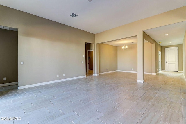 spare room featuring visible vents, light wood-style flooring, baseboards, and an inviting chandelier