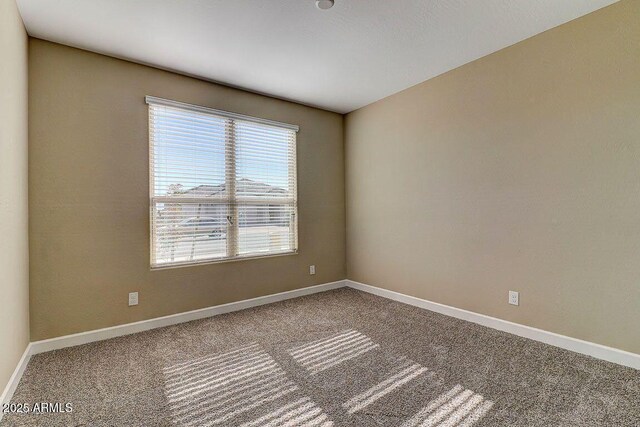 carpeted spare room featuring baseboards