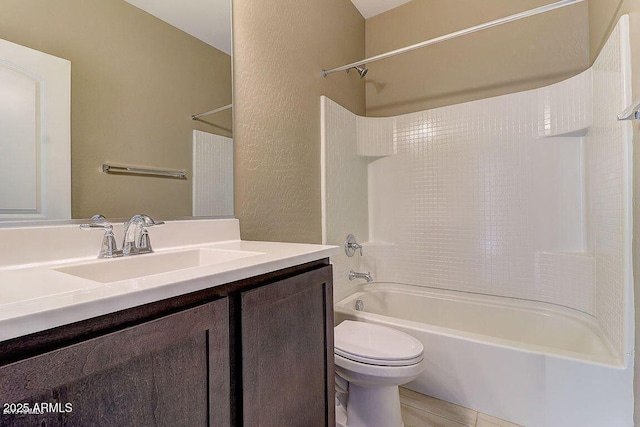 bathroom with a textured wall, shower / washtub combination, vanity, and toilet