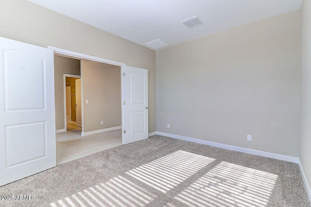 spare room with carpet, visible vents, and baseboards