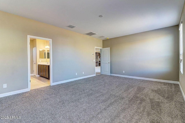 unfurnished bedroom with light carpet, connected bathroom, visible vents, and baseboards