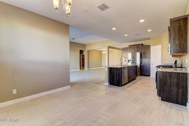 kitchen with a center island with sink, stainless steel appliances, visible vents, open floor plan, and dark brown cabinetry