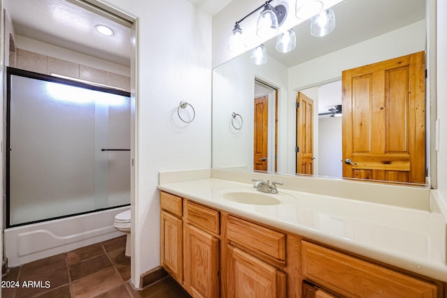 full bathroom with tile patterned flooring, bath / shower combo with glass door, vanity, and toilet