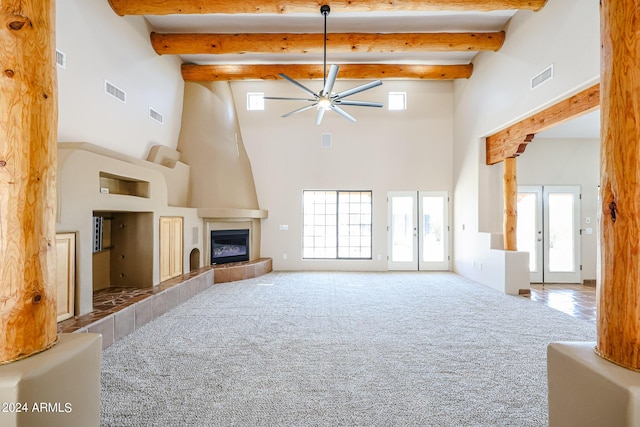 carpeted living room featuring a tile fireplace, ceiling fan, beam ceiling, and french doors