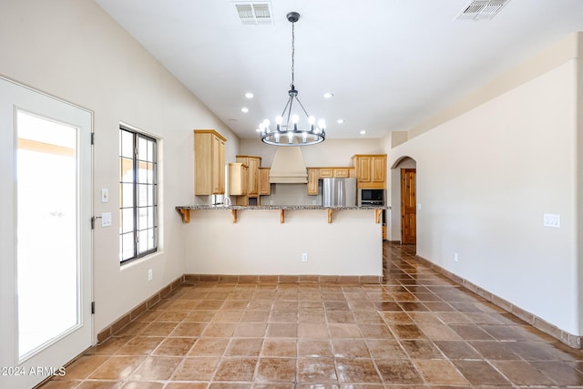 kitchen featuring stainless steel refrigerator, a kitchen breakfast bar, light brown cabinetry, and kitchen peninsula