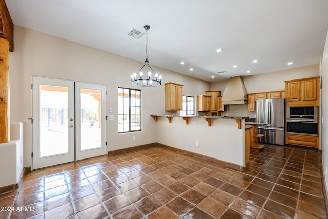 kitchen featuring custom exhaust hood, a breakfast bar area, dark stone countertops, kitchen peninsula, and stainless steel appliances