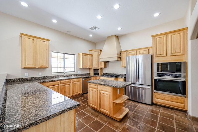 kitchen featuring sink, appliances with stainless steel finishes, a center island, custom range hood, and light brown cabinetry