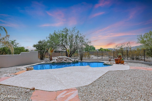 pool at dusk featuring a patio area