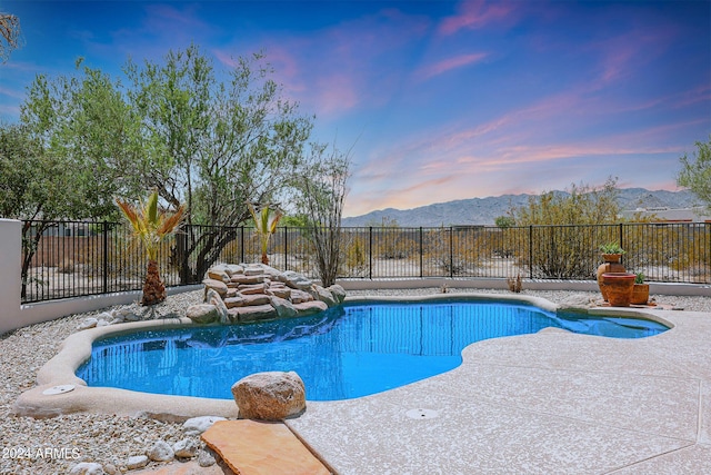 pool at dusk featuring a mountain view