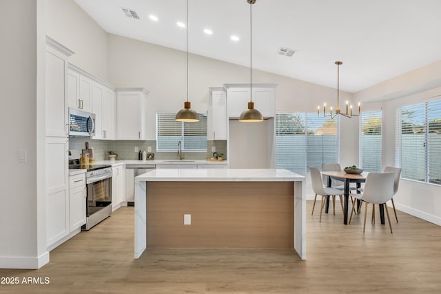 7685 W San Miguel Ave, Glendale, AZ 85303 - kitchen with stainless steel appliances, light wood-style flooring, backsplash, vaulted ceiling, and a chandelier