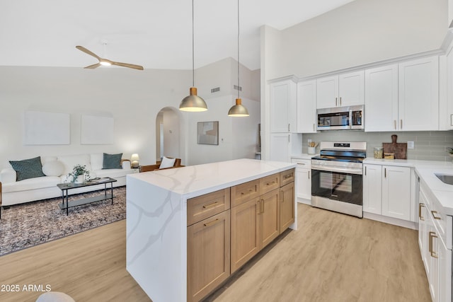 7685 W San Miguel Ave, Glendale, AZ 85303 - kitchen with stainless steel appliances, light wood finished floors, open floor plan, backsplash, and high vaulted ceiling