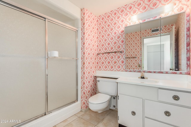 bathroom featuring tile patterned flooring, vanity, toilet, and walk in shower