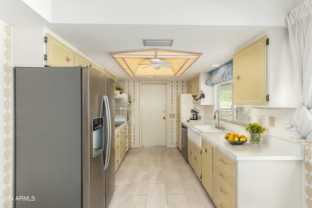 kitchen featuring light tile patterned floors, appliances with stainless steel finishes, sink, a tray ceiling, and ceiling fan