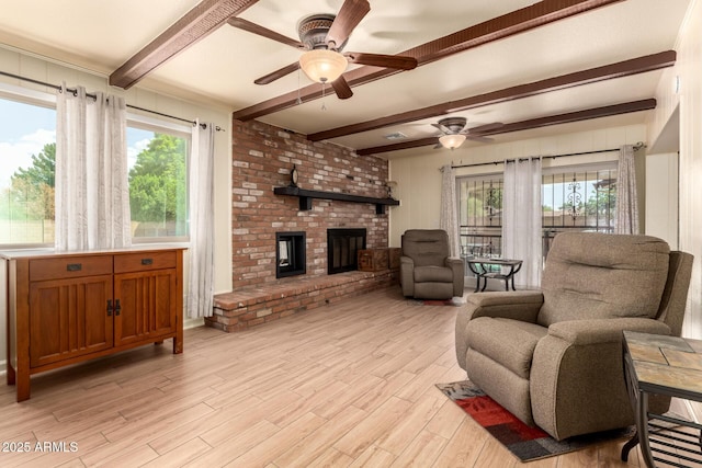 living area featuring light wood-style floors, a brick fireplace, a ceiling fan, and beam ceiling