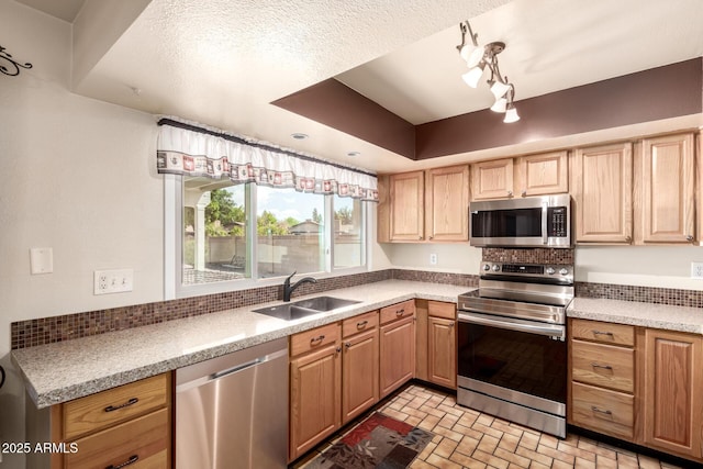 kitchen featuring brick patterned floor, light brown cabinets, a sink, light countertops, and appliances with stainless steel finishes