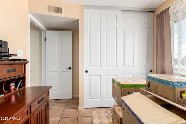 bedroom with light tile patterned floors, visible vents, a closet, and baseboards