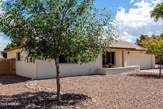 view of front of property with fence, an attached garage, stucco siding, and concrete driveway